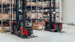 Two Linde MH very narrow aisle trucks with integrated personal protection system in front of the narrow-aisle warehouse