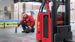 A Linde MH employee kneels in front of an L-MATIC and checks that everything is correct.