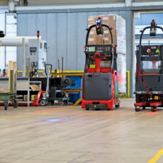 Two L-MATIC automatic pallet stackers transport goods between the packaging line and dynamic storage.